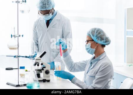biologi multiculturali in camici bianchi che eseguono test in laboratorio Foto Stock