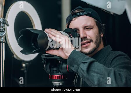 Videografo che guarda nel mirino della fotocamera in uno studio fotografico Foto Stock