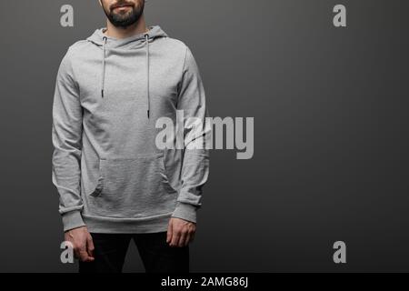 vista dal taglio corto di uomo con cappuccio grigio bianco su sfondo nero Foto Stock