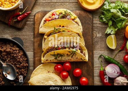 Vista dall'alto dei tacos messicani tradizionali con ingredienti biologici su sfondo di legno Foto Stock