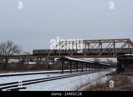 Vecchia stazione ferroviaria abbandonata in inverno a Chicago, in zona Englewood, con un treno CTA Green Line che lo attraversa su un ponte Foto Stock