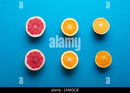 Agrumi freschi tagliati a metà su sfondo blu. Sopra la vista di metà di arance, cioccolato arancione e pompelmo. Frutti tropicali. Spuntini sani. Foto Stock