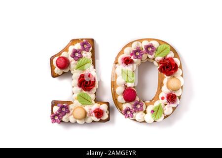 Numero dieci torta decorata con fiori e macarons isolato su sfondo bianco. Foto Stock