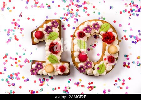 Numero dieci torta decorata con fiori e macarons isolato su sfondo bianco. Foto Stock
