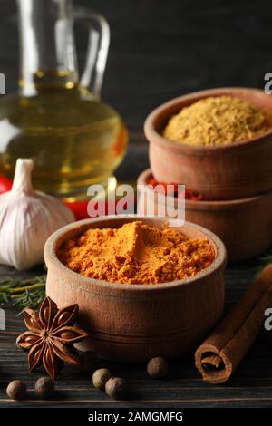 Ciotole con spezie e ingredienti su sfondo di legno, primo piano Foto Stock