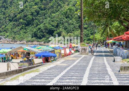 Guaruja - SP, Brasile - 20 novembre 2019: Marciapiede fronte spiaggia con ristoranti e tende della spiaggia Praia do Guaiuba. Foto Stock