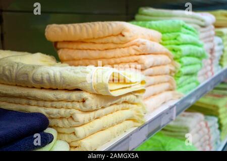 Asciugamani di spugna colorati. Vendita snuggly, giallo, textures asciugamani da bagno su una mensola. Fuoco selettivo. Vendita di accessori per la vasca Foto Stock