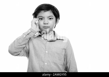 Studio shot di carino ragazzo giapponese parlando al telefono cellulare Foto Stock
