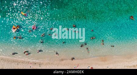 Veduta Aerea Da Flying Drone Di Persone Folla Divertirsi, Giocare E Rilassarsi In Acqua Nella Zona Di Parga, Mar Ionio, Epiro, Grecia Foto Stock