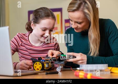 Insegnante Che Aiuta La Pupilla Femminile A Costruire La Macchina Del Robot Nella Lezione Di Scienza Foto Stock