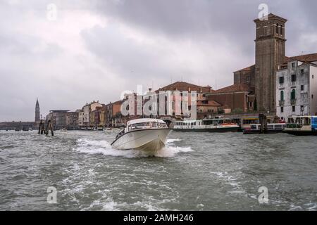 Venezia, ITALIA - 29 ottobre 2019: Il motoscafo salpa velocemente fuori dall'argine alla chiesa di Gesuiti, sparato il 29 ottobre 2019 in luminosa luce autunnale torbida a Veni Foto Stock