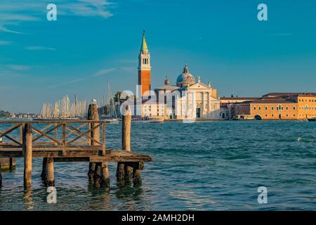 Tramonto a Venezia. Il primo piano è un molo di legno dove le gondole sono parcheggiate. Foto Stock