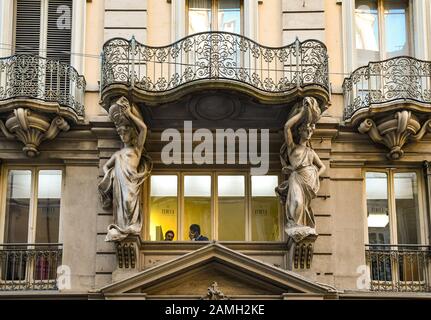 Facciata in stile barocco di un palazzo decorato con una coppia di cariatidi che sorreggono un balcone in via Garibaldi nel centro di Torino, Piemonte, Italia Foto Stock