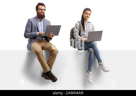 Studente femminile e uomo con bearded seduto su una scheda vuota e utilizzando computer portatili isolati su sfondo bianco Foto Stock