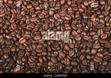 Chicchi di caffè marrone appena tostato, vista dall'alto della struttura dei semi come sfondo alimentare per il design. Foto Stock