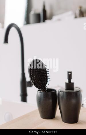 Vetro in ceramica nera con calcolo dei capelli e flacone per sapone liquido. Elegante doccia e accessori per la cura del corpo. Spa e concetto di relax Foto Stock
