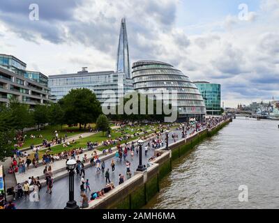 Folle di persone che si rilassano sulla riva sud vicino al Tamigi con lo Shard sullo sfondo di Londra Foto Stock