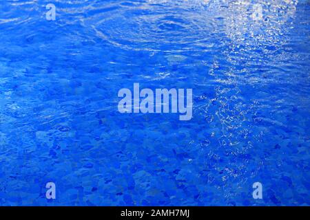 Lo sfondo è blu acqua in piscina con onde e bagliore di luce Foto Stock