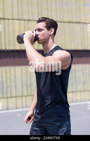 Giovane atleta acqua potabile dopo il jogging Foto Stock