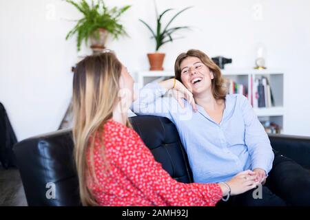 Due amici su un divano nel soggiorno di casa Foto Stock