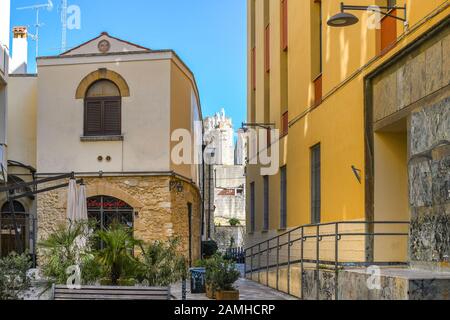 Un piccolo cortile nel centro turistico di Brindisi con le statue del Duomo di Brindisi visibili alle spalle in una giornata di sole nella regione Puglia. Foto Stock