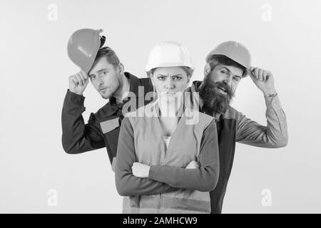 Donna, leader in cappello duro con faccia seria in piedi davanti ai costruttori. Concetto di Lady boss. Team di architetti, costruttori, operai che si alleano dietro donna isolato sfondo bianco. Foto Stock