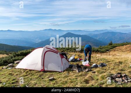 Campo base in montagna. Un turista raccoglie le cose per un'escursione. Foto Stock