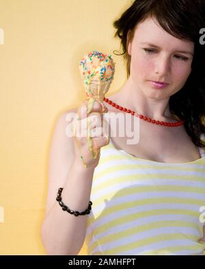 Giovane donna che tiene il cono del gelato fondente con le centinaia e le migliaia su di esso Foto Stock