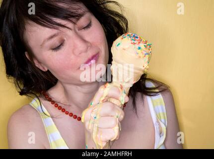 Giovane donna che tiene il cono del gelato fondente con le centinaia e le migliaia su di esso Foto Stock