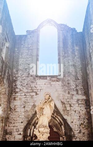 Scultura di Giovanni di Nepomuk nel convento di Carmo e arco della finestra illuminato dal sole primaverile. Foto Stock