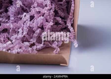 Carta da triturare viola da vicino in una scatola di cartone. Foto Stock