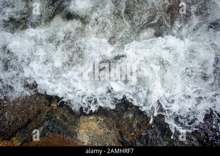 Onde oceaniche durante la tempesta. L'acqua rotola in avanti e bolle a riva, forza della natura e polvere beatyful acquamarine blu . Foto Stock