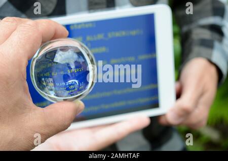 sfera di cristallo in mano sullo sfondo di un tablet sfocato con uno schermo blu, la procedura di riparazione dopo gli attacchi hacker, un concetto di avviso Foto Stock