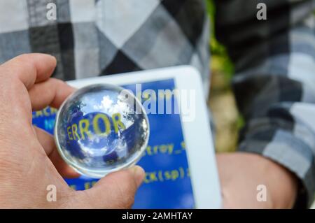 sfera di cristallo in mano con la parola "errore" sullo sfondo di un tablet con uno schermo blu, la procedura di riparazione dopo gli attacchi hacker Foto Stock