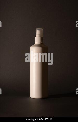 Flacone bianco di detergente su fondo nero. Telaio verticale Foto Stock