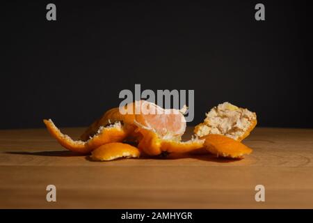 Bucce di mandarino su una superficie di legno su uno sfondo scuro Foto Stock