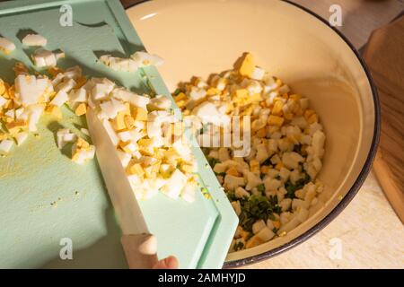 Le mani del cuoco tagliano uova e patate per insalata. Cibo vegetariano sano e naturale Foto Stock