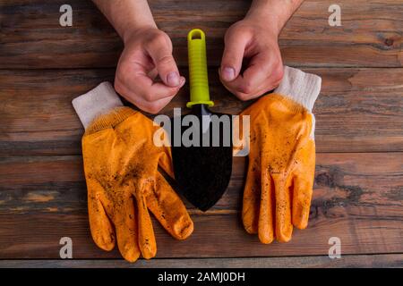 Paio di guanti, trowel e mani di uomini - concetto di giardinaggio. Foto Stock