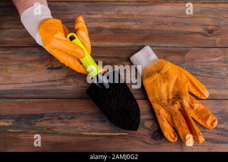 La mano dell'uomo tiene la pala da giardino con il terreno. Foto Stock