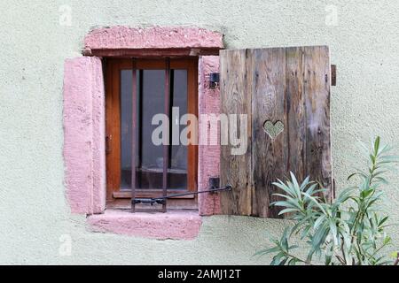 Piccola e vecchia finestra con bar e una sola serranda in legno Foto Stock