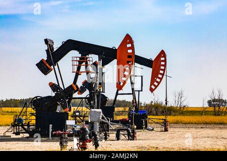 Dettagli di due pozzi di petrolio in Canada rurale. Aka annuendo cavalli, asini, pompe. Contrappeso e manovella con traversa di calpestio. Estrazione di risorse finite Foto Stock