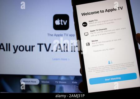 San Pietroburgo, Russia - 10 gennaio 2020: Telefono cellulare con app Apple TV sullo schermo primo piano con sito web su laptop, Editoriale Illustrativa Foto Stock