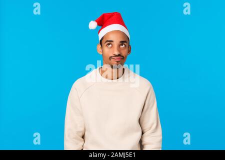 Il peggior anno nuovo di sempre. Il ragazzo afro-americano arrabbiato e angosciato giovane scettico non sente l'umore di natale, in piedi triste e deluso, indossando santa Foto Stock