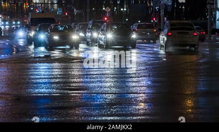 auto sulla strada notturna della città. strada bagnata dopo la prima nevicata Foto Stock