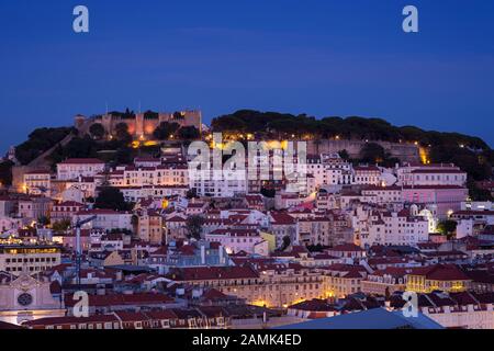 Vista panoramica del castello di Sao Jorge (Saint George Castle, Castelo de Sao Jorge) e il quartiere di Alfama nel centro di Lisbona, Portogallo, la sera. Foto Stock