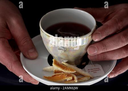 Uomo che tiene una tazza fresca di tè / tè a base di erbe nero nella tazza / Ancora vita fotografia di cibo Foto Stock