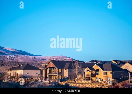 Case distanti contro colline coperte di neve giorno luce Foto Stock