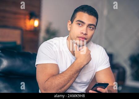 Ragazzo giovane atletico che guarda pensieroso al lato. Foto Stock