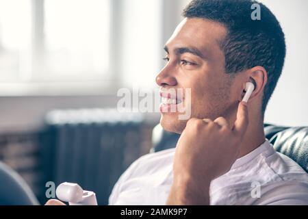 Piuttosto ragazzo che ascolta la musica tramite cuffie wireless. Foto Stock