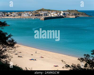 Sabbiosa spiaggia di Porthminster con il Cornish cittadina balneare e di villeggiatura di St. Ives al di là su soleggiate giornate estive, Cornwall, Regno Unito Foto Stock